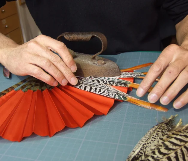 Placement de plumes de faisan sur une feuille de soie corail © Frédérick Gay